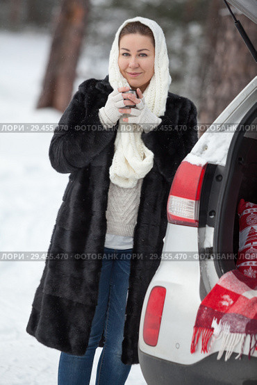 Young woman standing near suv and holding tea mug in hands at winter season. Стоковое фото, фотограф Кекяляйнен Андрей / Фотобанк Лори