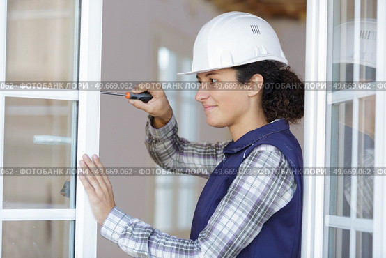 young woman unscrews the fixing screws of the window handle. Стоковое фото, агентство Ingram Publishing / Фотобанк Лори