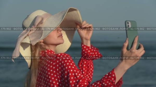 Young woman using smartphone making video selfie on beach on background of ocean waves. Стоковое видео, видеограф А. А. Пирагис / Фотобанк Лори