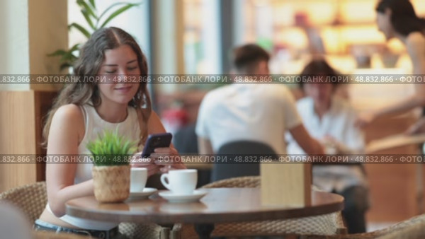Young woman with phone in cafe. Стоковое видео, видеограф Яков Филимонов / Фотобанк Лори
