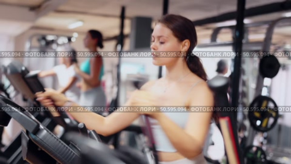 Young woman working out on elliptical machine. Стоковое видео, видеограф Яков Филимонов / Фотобанк Лори