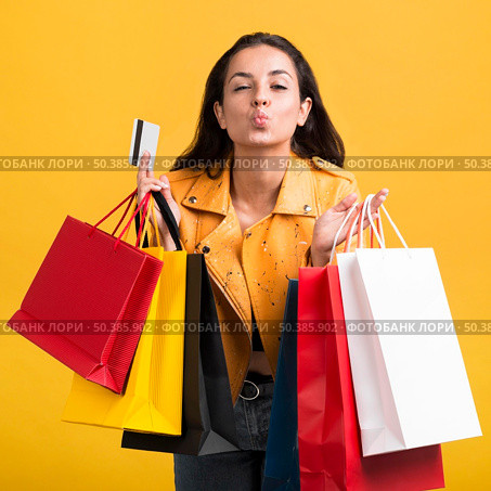 young woman yellow leather jacket with shopping bags. Стоковое фото, агентство Ingram Publishing / Фотобанк Лори