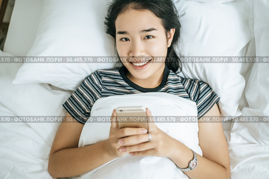 Young women wearing striped shirts playing smart phones. Selective focus. Стоковое фото, агентство Ingram Publishing / Фотобанк Лори