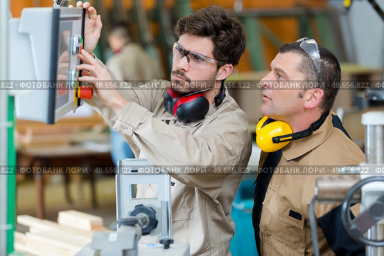 young worker pressing controls for workshop machinery. Стоковое фото, агентство Ingram Publishing / Фотобанк Лори
