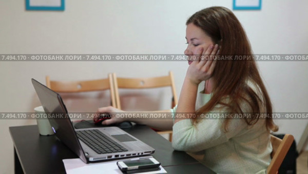 Задумчивая спокойная девушка сидит за столом, работает на ноутбуке. Стоковое видео, видеограф Кекяляйнен Андрей / Фотобанк Лори
