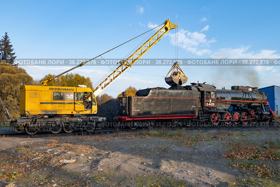 Железнодорожный кран КЖ-462 "Первомаец" загружает углем старый советский  паровоз серии "Л" (Л-4429, Лебедянка) октябрьским утром. Станция Сортавала (2021 год). Редакционное фото, фотограф Виктор Карасев / Фотобанк Лори