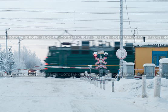 Железнодорожный переезд с проносящимся локомотивом. Зимнее время года. Стоковое фото, фотограф Кекяляйнен Андрей / Фотобанк Лори