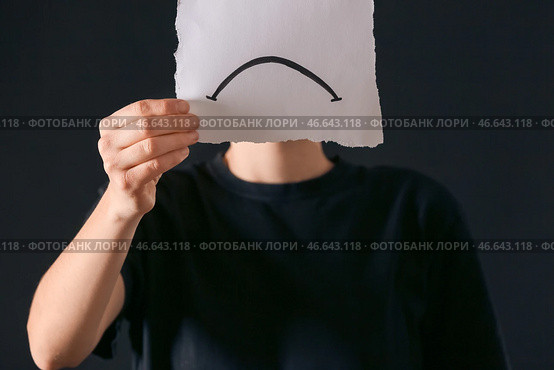 Женщина, держащая бумажный лист с нарисованным печальным ртом на темном фоне. Понятие депрессии. Стоковое фото, фотограф Pixel_shot / Фотобанк Лори