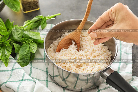Женщина добавляет специи к вкусному рису в кастрюле. Стоковое фото, фотограф Pixel_shot / Фотобанк Лори