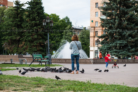Женщина-мать кормит голубей, а ребенок катается на трехколесном велосипеде (2019 год). Редакционное фото, фотограф Кузин Алексей / Фотобанк Лори