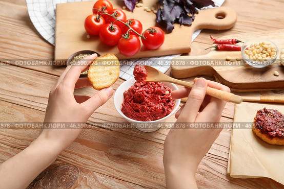 Женщина намазывает вкусный соус песто на тосты на деревянном фоне. Стоковое фото, фотограф Pixel_shot / Фотобанк Лори