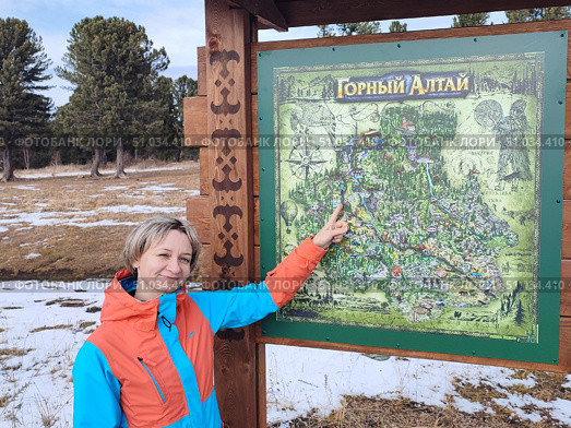 Женщина показывает на карту Горного Алтая с достопримечательностями. A woman points to a map of Gorny Altai with its sights. (2022 год). Редакционное фото, фотограф Денис Баданин / Фотобанк Лори