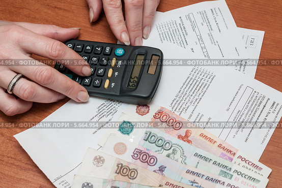 Женщина рассчитывает на калькуляторе семейный бюджет на коммунальные расходы (2014 год). Редакционное фото, фотограф Игорь Низов / Фотобанк Лори
