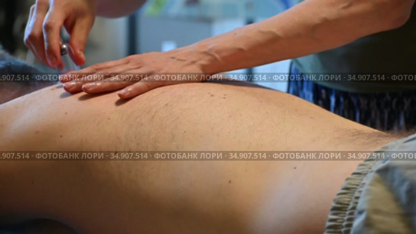 Женские руки массируют спину мужчины с помощью вакуумных банок. Massage with a vacuum jar at home. Стоковое видео, видеограф Владимир Литвинов / Фотобанк Лори