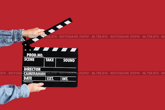Женские руки с хлопушкой для фильма на красном фоне. Стоковое фото, фотограф Pixel_shot / Фотобанк Лори