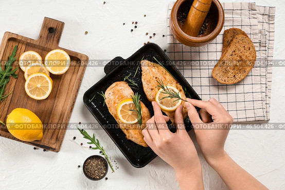 Женские руки с жареной куриной грудкой, специями и лимонами на светлом фоне. Стоковое фото, фотограф Pixel_shot / Фотобанк Лори