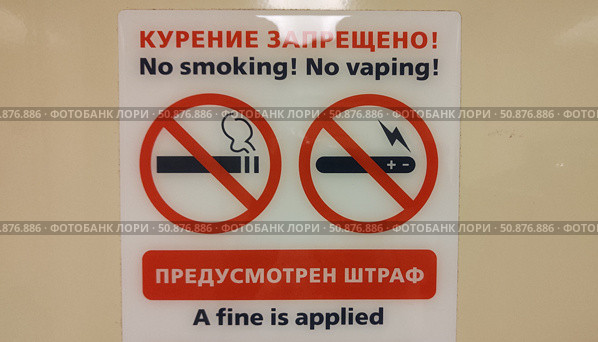 Знаки и надписи на русском и английском языках. Курение запрещено. Предусмотрен штраф. Правила нахождения в помещении. Забота о здоровье посетителей. Табличка на стене туалета. Крупный план. Signs and inscriptions in Russian and English. No smoking. No vaping. A fine is applied. Indoor rules. Taking care of health of visitors. Sign on the toilet wall. Close-up. Стоковое фото, фотограф Ирина / Фотобанк Лори