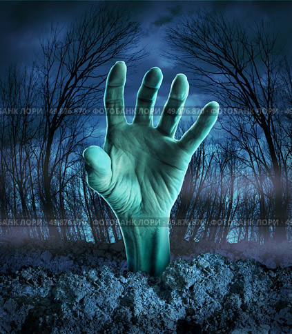 Zombie hand rising out of the ground in a spooky dark forest with creepy trees and fog as a symbol of Halloween imagination with a dangerous monster coming back from the dead. Стоковое фото, агентство Ingram Publishing / Фотобанк Лори