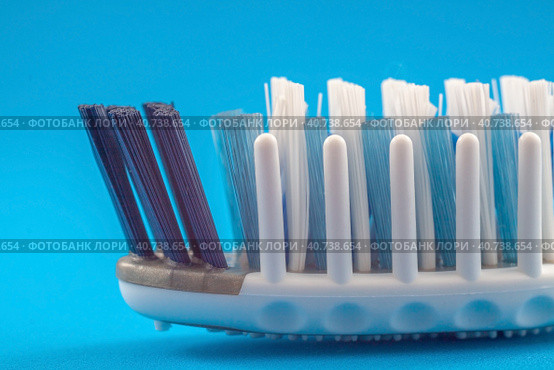 Зубная щетка с массажными щетинками крупным планом. The toothbrush head with massaging bristles close-up on a blue background. Caring for healthy teeth and gums. Стоковое фото, фотограф Валерий Елистратов / Фотобанк Лори